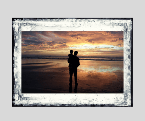 Silhouette of a man holding a small child on a beach at sunset. Signifies men and child custody during divorce. 