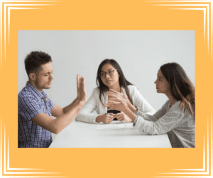 The start of the divorce mediation process. Man and woman argue across a table with a divorce mediator present. 